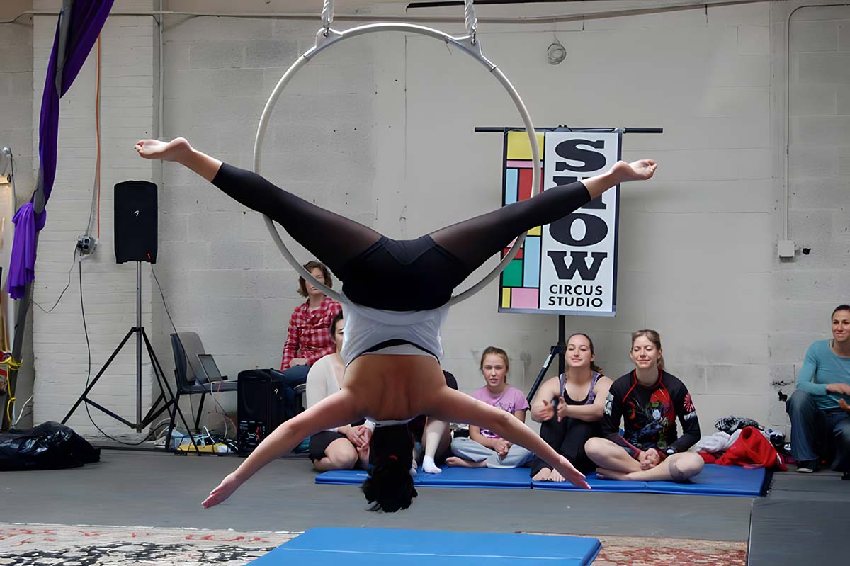 Performer demonstrating hanging upside down on a lyra (ring) at SHOW Circus Studio in Easthampton, Massachusetts