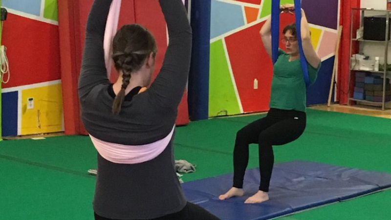 Two circus practitioners hanging from fabric set up as a lifting strop at SHOW Circus Studio in Easthampton, Massachusetts